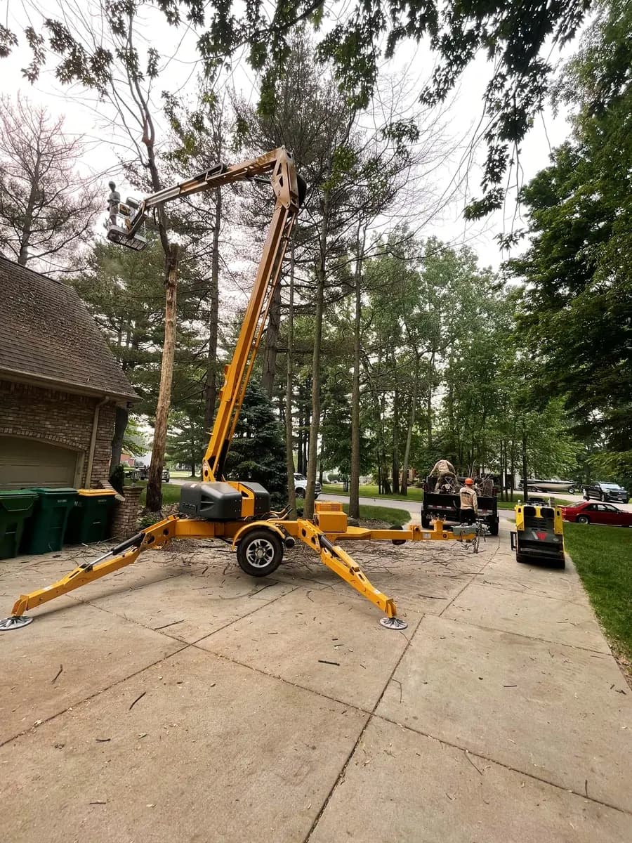 A lift set up on a driveway to reach a tree leaning over a house in North Alabama