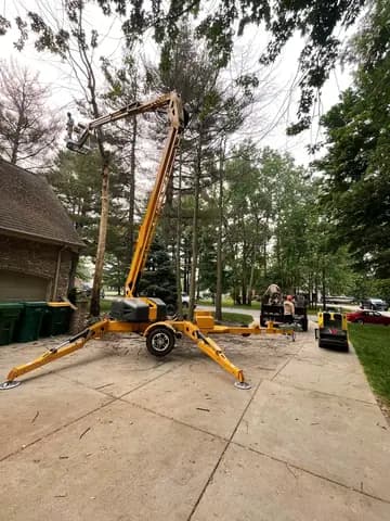 The lift is set on the driveway to reach a tree leaning over the house.